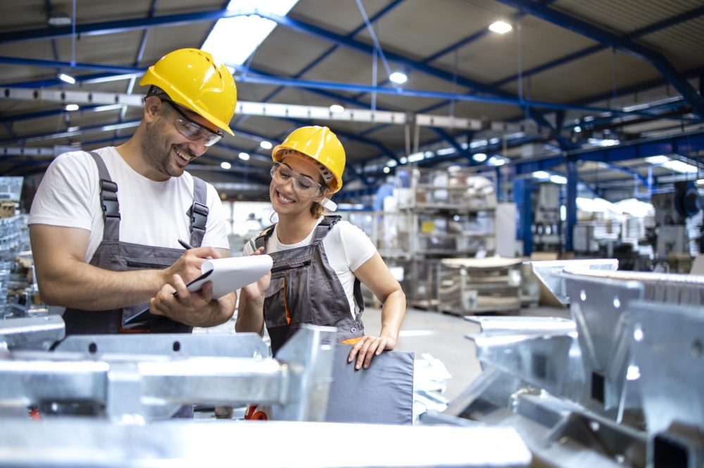 Factory workers checking quality of products in large industrial hall.